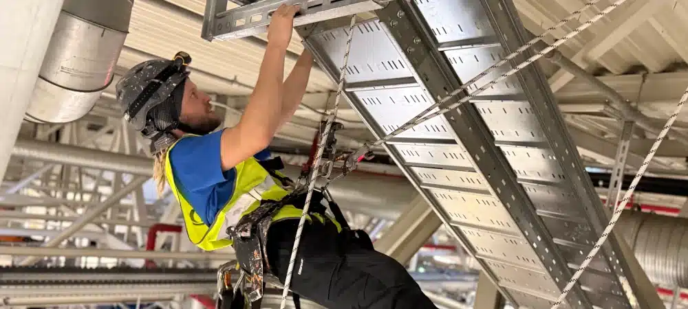 FISAT-zertifizierter Industriekletterer von IKT Berlin bei Kabeltrassenmontage im BMW-Werk Leipzig — Seilzugangstechnik über laufender Automobilproduktion